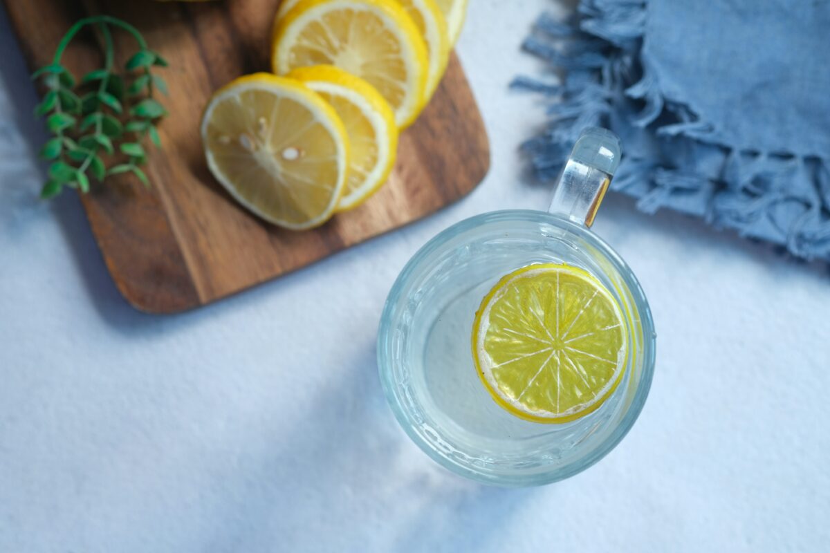 Verre d'eau citronnée détox posé sur une table le matin, à côté d'un demi-citron pressé
