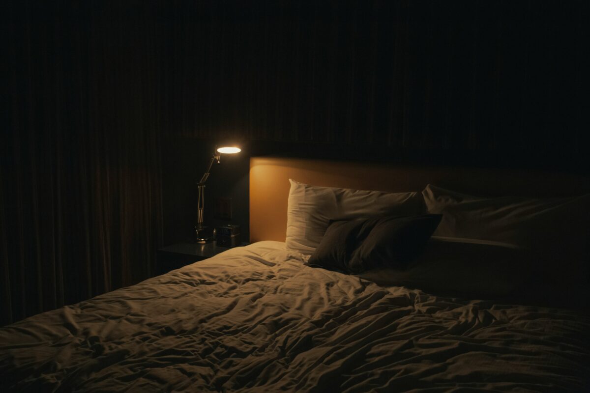 Smartphone posé loin du lit dans une chambre sombre, illustrant la coupure des écrans le soir avant de dormir