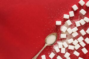 Cuillère de sucre en poudre, comparée aux édulcorants artificiels qui perturbent le microbiote
