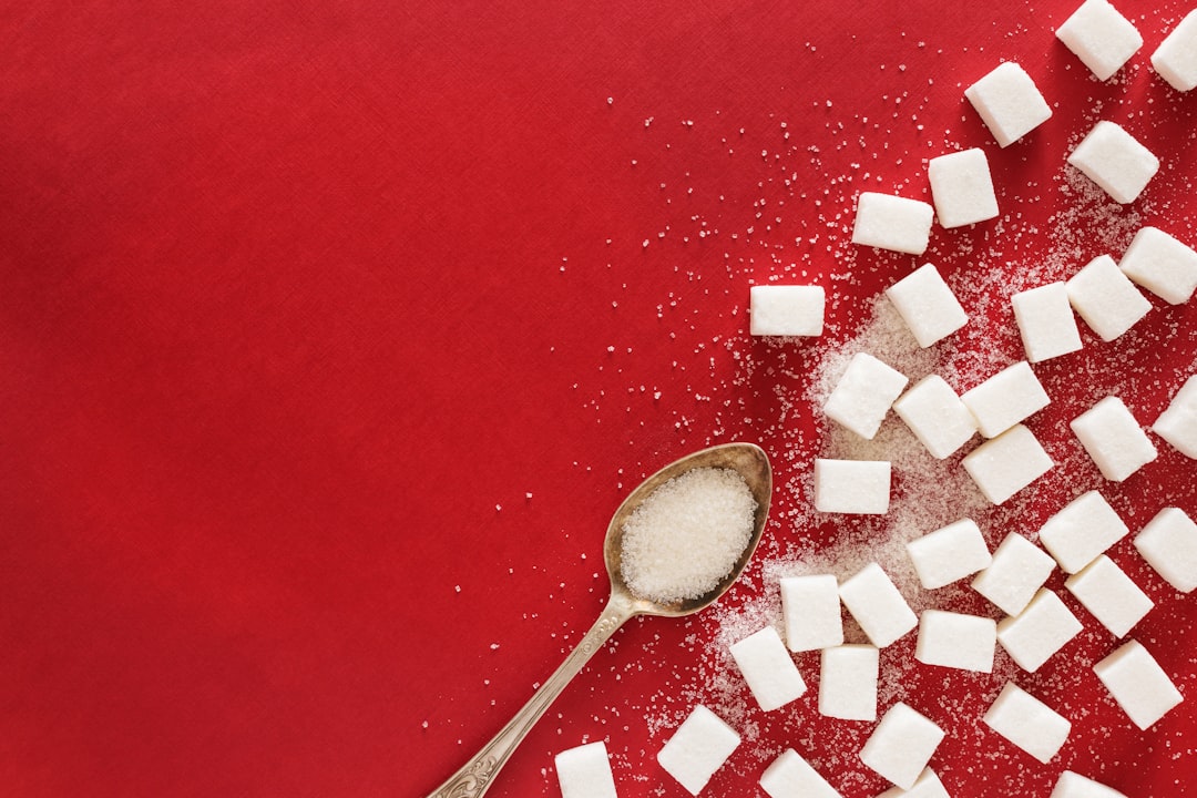 Cuillère de sucre en poudre, comparée aux édulcorants artificiels qui perturbent le microbiote