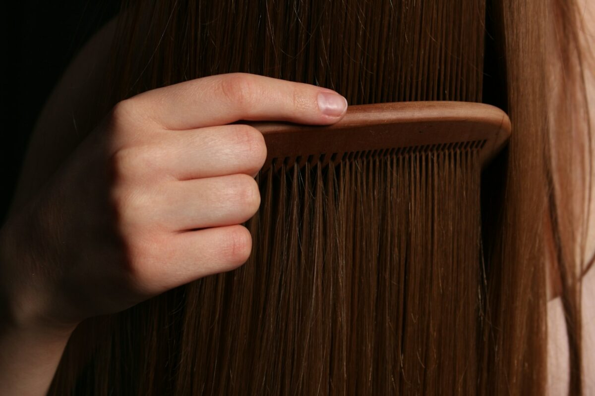Main qui peigne de longs cheveux, soin au beurre de mangue pour cheveux secs