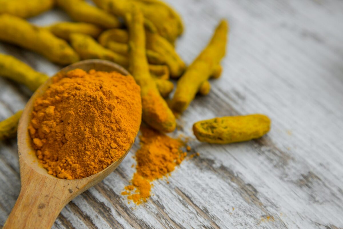 Curcuma anti-inflammatoire en poudre et racine fraîche sur fond bois