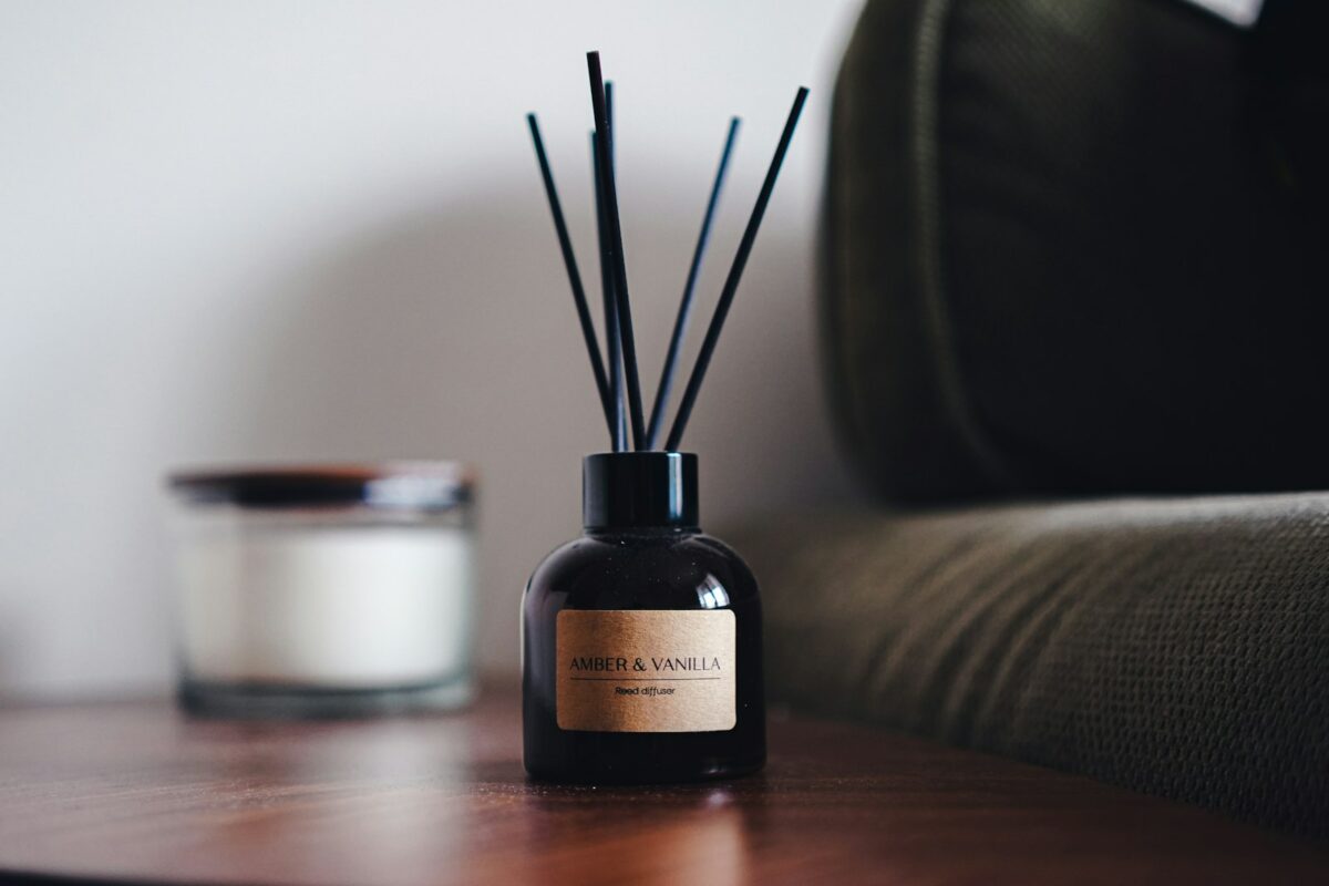 Diffuser des huiles essentielles : diffuseur à roseaux et bougie posés sur une surface en bois