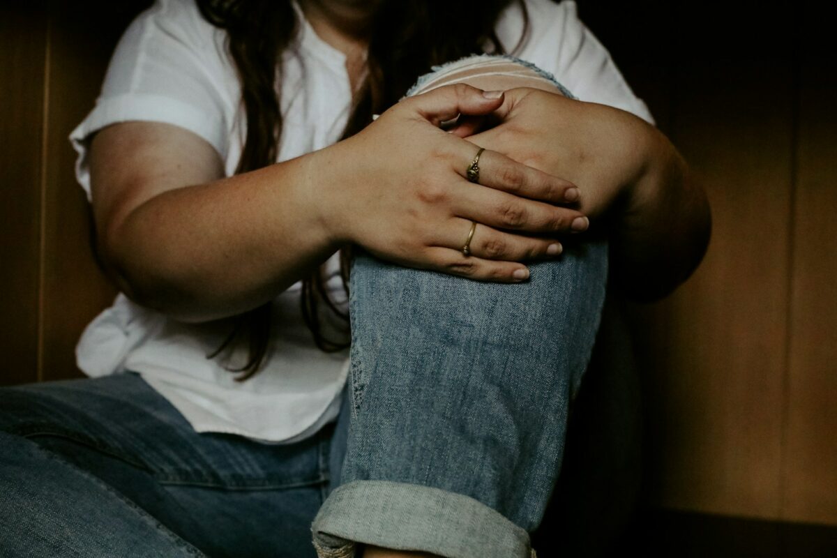 Douleur dans le mollet : femme assise au sol, les mains sur les genoux