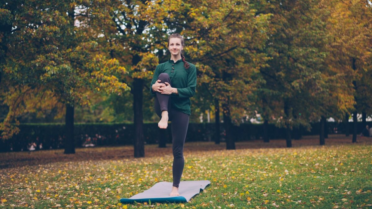 Femme en équilibre sur un pied sur un tapis de yoga, pour travailler l'équilibre sur un pied