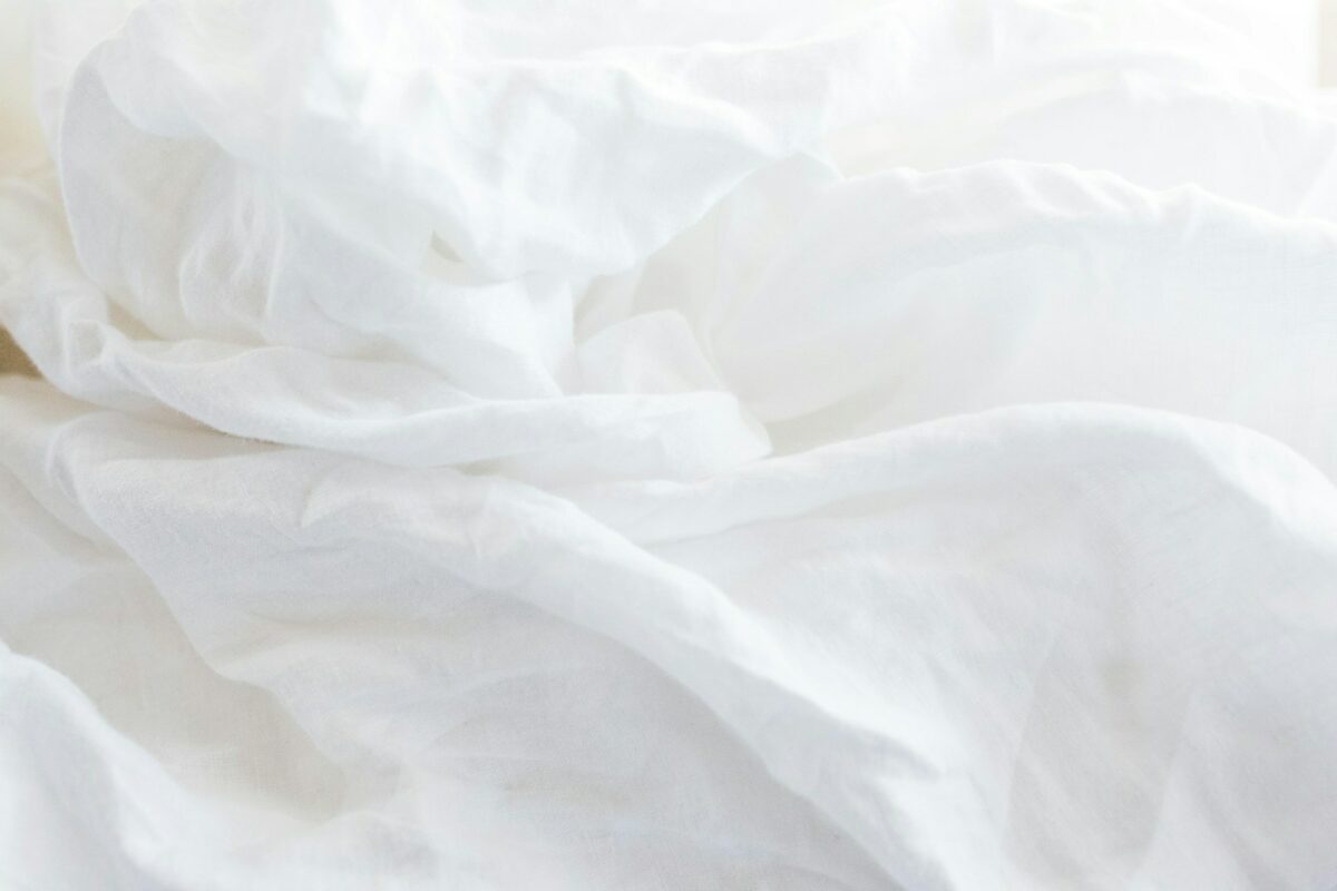Faire son lit : literie blanche en lin dans une chambre lumineuse