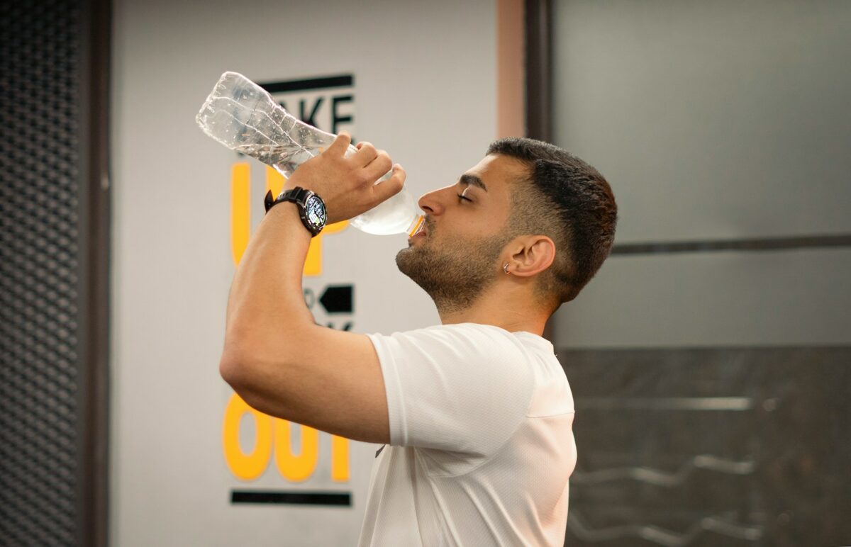 Sportif qui boit à sa gourde, hydratation à l'entraînement