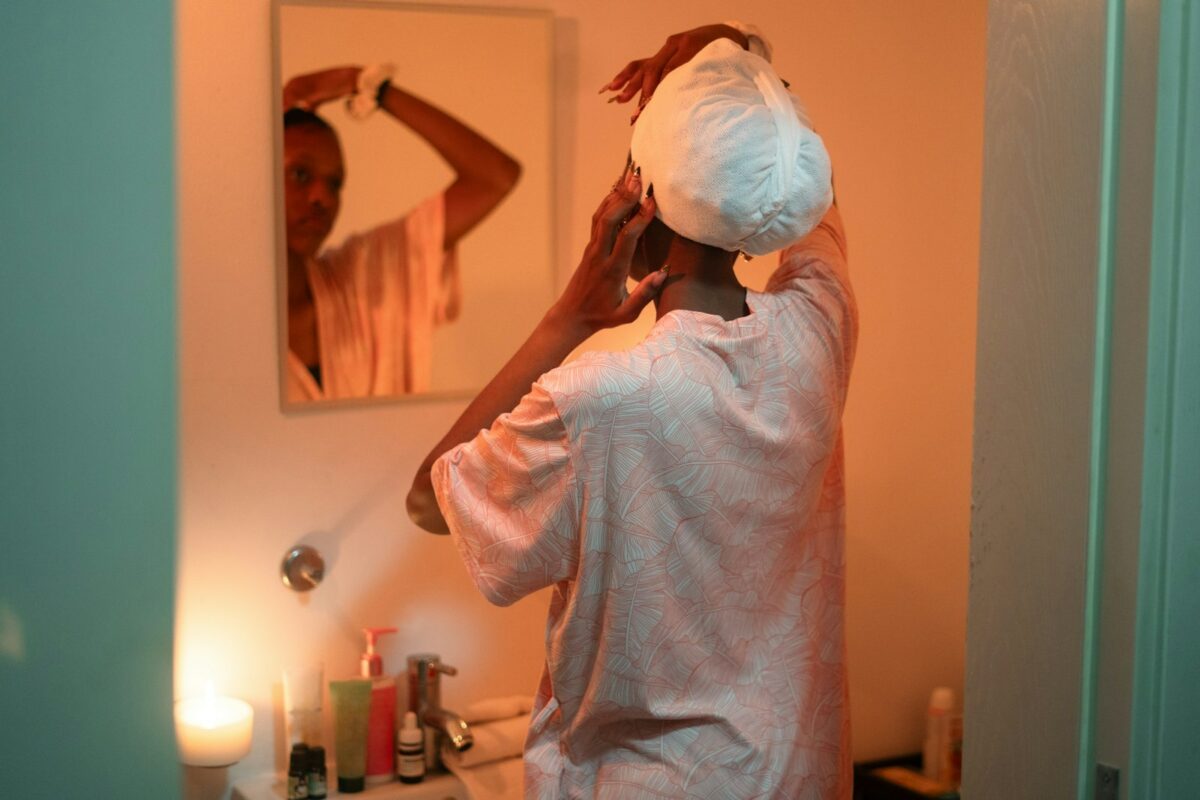 Masque au fenugrec : femme séchant ses cheveux devant le miroir de la salle de bain