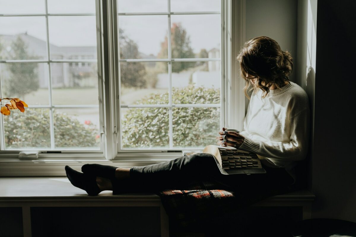 Niksen : une femme assise sur un rebord de fenêtre, au repos
