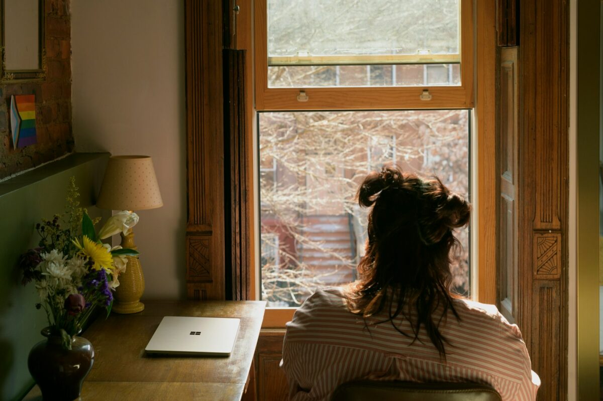 Règle 20-20-20 : femme assise qui regarde par la fenêtre pour reposer ses yeux