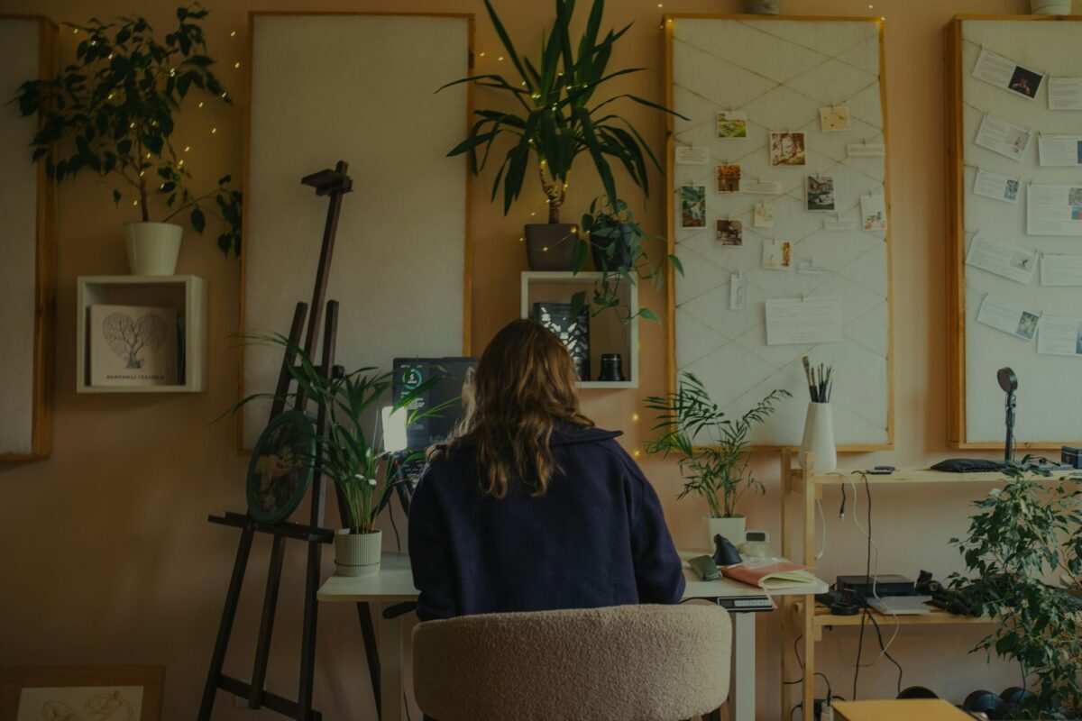 Règle des 2 minutes : une femme concentrée à son bureau dans un atelier plein de plantes